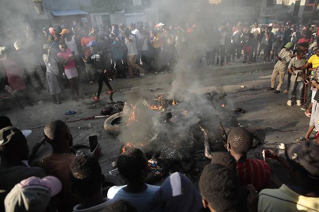 아이티 포르토프랭스에서 불에 탄 시신들을 사람들이 바라보고 있다. AP연합뉴스