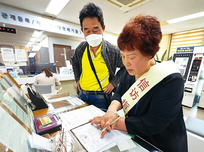 김상화씨(오른쪽)가 민원인의 신청 서류를 대신 작성하고 있다.