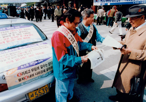 지난 1998년 1월 시민들이 금 모으기 행사에 동참을 호소하는 유인물을 나눠주고 있다. / 경향신문 자료사진