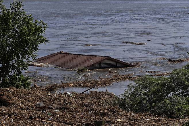 6일(현지시간) 우크라이나 남부 헤르손에서 노바 카호우카 댐이 붕괴된 후 범람한 드니프로 강에서 주택 지붕이 보인다. / 사진=로이터 연합뉴스