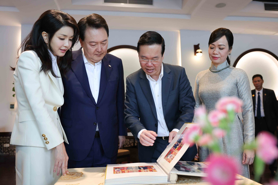 President Yoon Suk Yeol, center left, and first lady Kim Keon-hee, left, view a photo album gifted by Vietnamese President Vo Van Thuong, center right, and first lady Phan Thi Thanh Tam, right, after their breakfast meeting at a restaurant near Hoan Kiem Lake in Hanoi Saturday, the last day of the Korean leader’s three-day state visit. [JOINT PRESS CORPS]