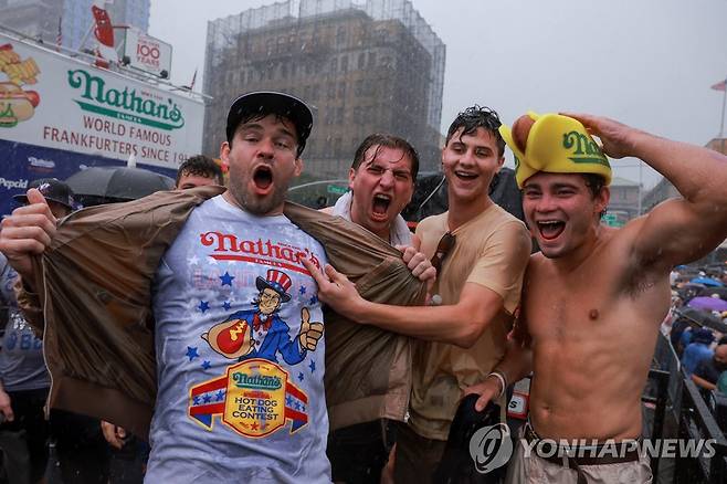비를 맞으며 행사장을 지키는 관중 (뉴욕 로이터=연합뉴스) 폭우 속에서도 핫도그 먹기 대회 행사장을 떠나지 않는 관중. 2023.7.4 photo@yna.co.kr