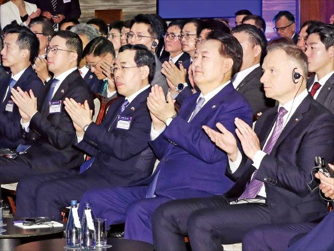 윤석열 대통령과 안제이 두다 폴란드 대통령이 14일 폴란드 바르샤바에서 열린 한·폴란드 비즈니스포럼에서 김병준 전국경제인연합회 회장 직무대행의 인사말을 들으며 박수를 치고 있다. 왼쪽부터 김동관 한화그룹 부회장, 구광모 LG그룹 회장, 이창양 산업통상자원부 장관, 윤 대통령, 두다 대통령. /연합뉴스