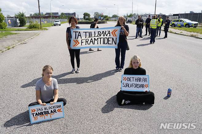 [말뫼=AP/뉴시스] 스웨덴 기후 운동가 그레타 툰베리(왼쪽)가 다른 운동가들과 함께 24일(현지시각) 스웨덴 말뫼의 석유 시설 입구 도로에서 시위하고 있다. 툰베리는 지난달 같은 곳에서 시위를 벌이던 중 교통에 방해가 된다는 이유로 장소를 옮기라는 경찰의 지시를 따르지 않은 '경찰 불복종' 혐의로 벌금형(약 30만 원)을 선고받은 지 불과 몇 시간 만에 다시 시위를 벌였다. 2023.07.25.