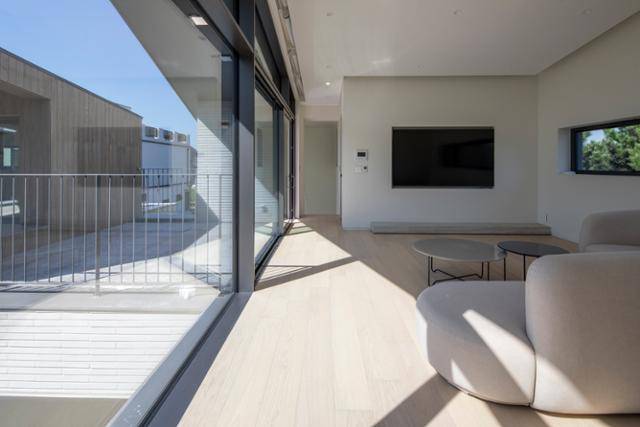 2층에서 바라본 거실 공간과 테라스. 4.5에 이르는 높은 천장고와 커다란 창, 거실과 연결된 나무 덱이 개방감을 선사한다. 김재윤 건축사진작가 제공