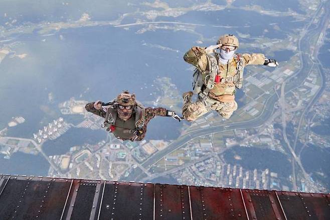 한미 특수전 요원들이 충남 계룡 일대 상공에서 연합·합동 고공강하를 위해 헬기에서 점프하며 거수경례를 하고 있다.