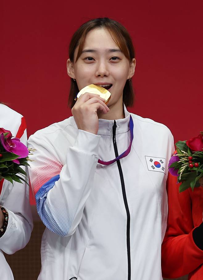 <YONHAP PHOTO-5889> 금메달 입에 무는 윤지수 (항저우=연합뉴스) 김인철 기자 = 26일 중국 항저우 전자대학 체육관에서 열린 19회 항저우 아시안게임 펜싱 여자 사브르 개인 결승전에서 금메달을 획득한 윤지수가 시상대에 메달을 입에 물고 포즈를 취하고 있다. 2023.9.26 yatoya@yna.co.kr/2023-09-26 22:43:17/ <저작권자 ⓒ 1980-2023 ㈜연합뉴스. 무단 전재 재배포 금지.>