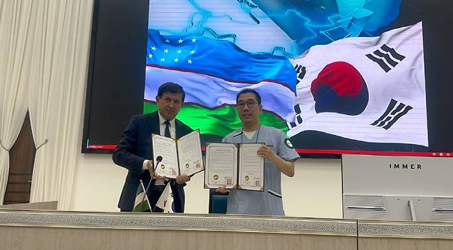 부하라 국립의과대학 총장(왼쪽)과 이승언 KOMSTA 단장이 MOU 체결식에서 기념 촬영을 하고 있다.