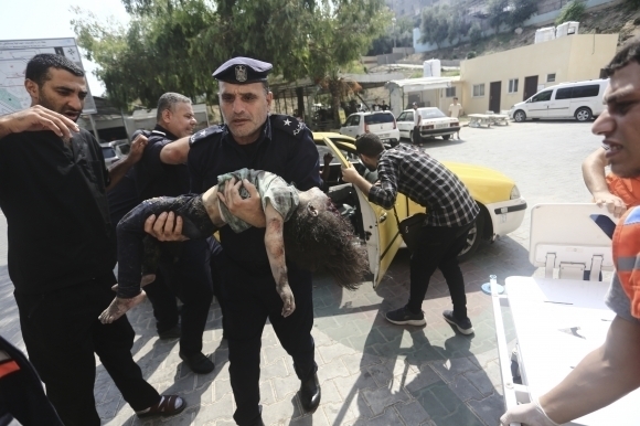 8일(현지시간) 팔레스타인 가자지구에서 하마스 경찰관이 이스라엘의 공습으로 부상당한 소녀를 병원으로 이송하고 있다. 2023.10.9 AP 연합뉴스