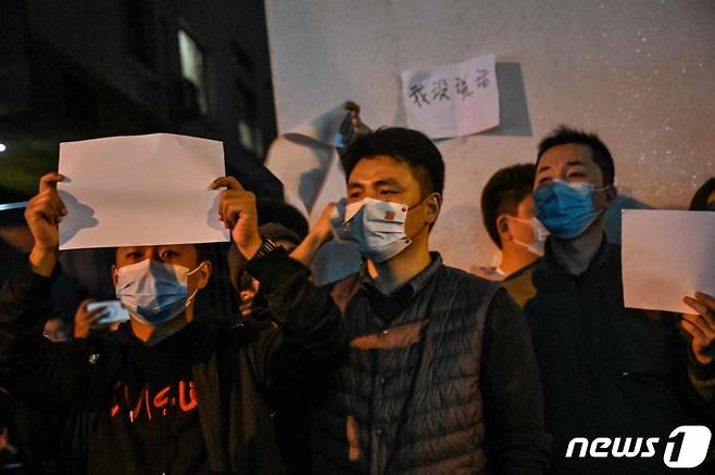 지난해 11월 27일(현지시간) 중국 상하이에서 정부의 고강도 제로 코로나19 봉쇄 정책에 항의하고 우루무치 화재 희생자를 추모하는 주민들이 정부에 항의하는 의미를 담은 ‘백지’를 들고 시진핑 주석의 퇴진을 요구하는 밤샘 시위를 하고 있다. /AFPBBNews=뉴스1