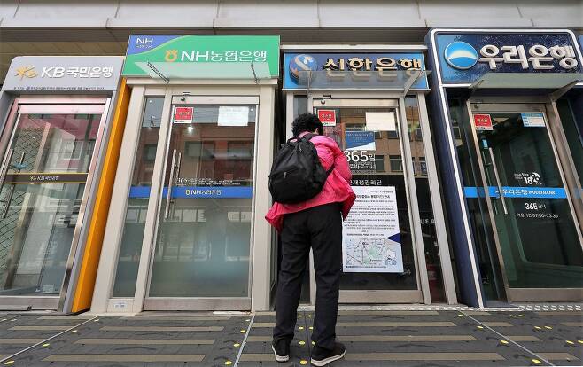 국민들의 물가 부담을 낮추려면 금융개혁을 통해 은행들의 대출이자를 낮추는 것도 필요하다. 지난 5월 22일 서울 시내 은행 현금인출기 앞에서 한 시민이 순서를 기다리고 있다./연합뉴스