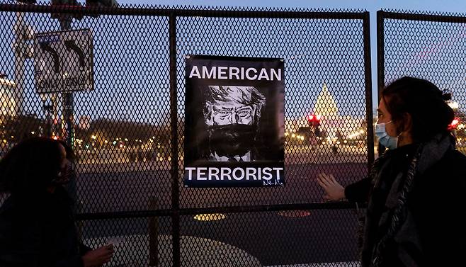 트럼프 대통령에 대한 두 번째 탄핵소추안이 가결된 13일(현지 시각) 워싱턴 DC의 의사당 앞 펜스에 시민들이 그를 '테러리스트'로 표현한 게시물이 걸려있다./연합뉴스