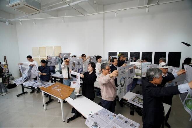 지난 5월 서울 자하미술관 전시장에서 30여명의 참석자들이 동참한 가운데 펼쳐진 성능경의 신문 읽고 오리기 퍼포먼스 장면. 자하미술관 제공