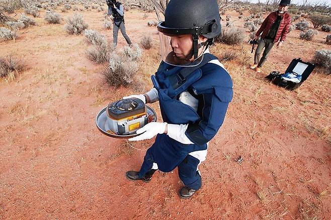 일본우주항공연구개발기구관계자가 2020년 12월 하야부사2가 호주 우메라사막에 떨어뜨린 소행성 ‘류구’의 토양이 담긴 캡슐을 회수하고 있다./뉴시스