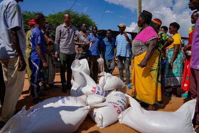 지난달 26일 케냐 타나리버 카운티 방갈레 마을에서 주민들이 식량 배급을 받고 있다. AP 뉴시스