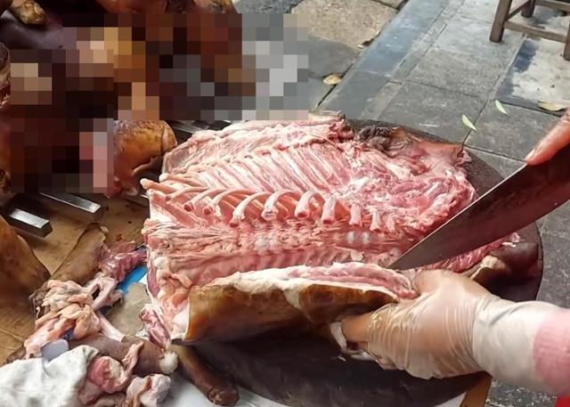지난달 30일 베트남 하노이에서 한 상인이 개고기를 해체하고 있다. 매대 옆으로 까맣게 그을린 개가 원래 형태 그대로 놓여있다. 하노이=허경주 특파원