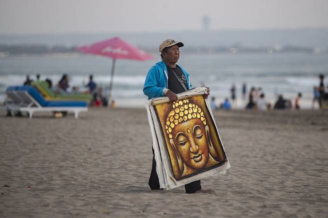 지난 8월 1일 인도네시아 발리섬 세미냑의 해변에서 현지 행상인이 그림을 팔기 위해 관광객을 찾고 있다.EPA연합뉴스