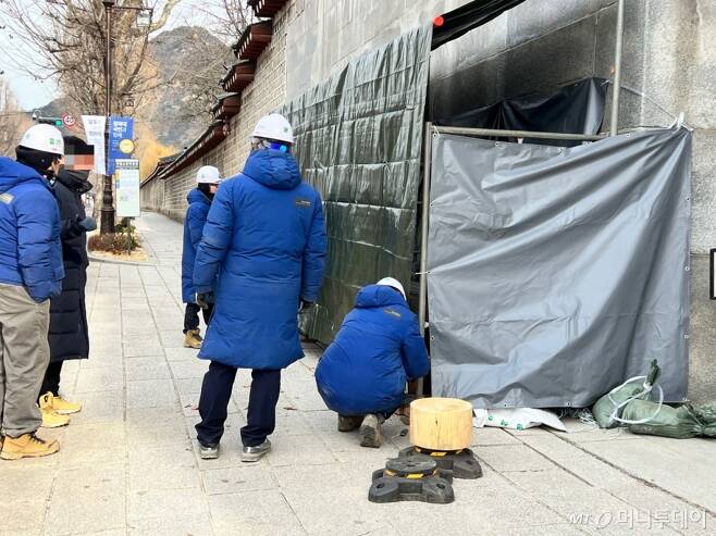 18일 오전 11시22분쯤 서울 종로구 경복궁 영추문 좌측 담장에 파란색 점퍼를 입은 경복궁관리소 관계자들이 철근 구조물에 녹색 천막을 씌워 작업 공간을 만들고 있다./사진=민수정 기자