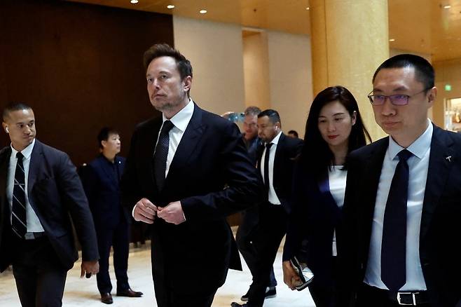 지난 5월 중국을 방문한 일론 머스크 테슬라 CEO가 베이징의 한 호텔을 나서고 있다. 톰 주 자동차 부문 수석 부사장(맨 오른쪽)과 그레이스 타오 부사장(두 번째)이 뒤따르고 있다. 로이터