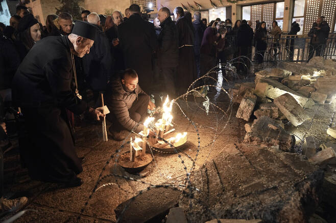 성직자와 사람들이 서안지구 베들레헴의 구유광장에서 23일(현지시간) 가자지구 희생자들을 기리기 위한 예수 탄생 재현 장면을 장식하고 있다. AP연합뉴스