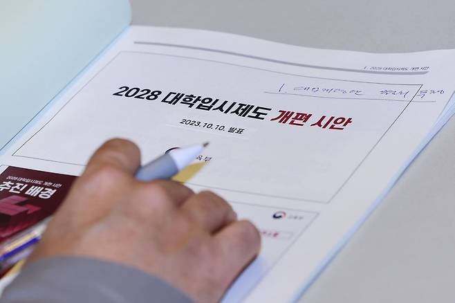 지난 11월 서울 영등포구 여의도 FKI타워에서 열린 2028 대학입시제도 개편 시안 공청회에서 한 참석자가 관련 책자를 살피고 있다. /연합뉴스