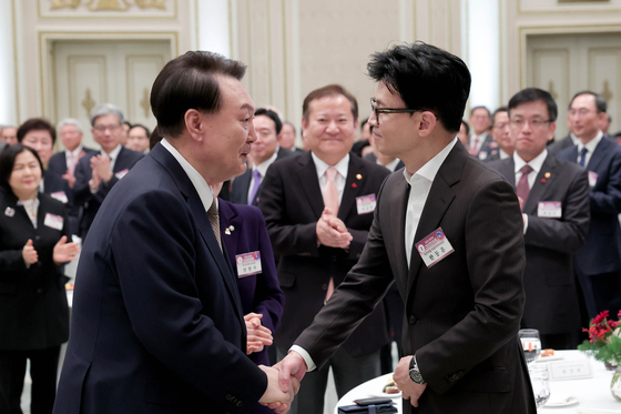 President Yoon Suk Yeol, left, shakes hands with Han Dong-hoon, interim leader of the conservative People Power Party and former justice minister, at the Blue House in Seoul on Wednesday. [JOINT PRESS CORPS]