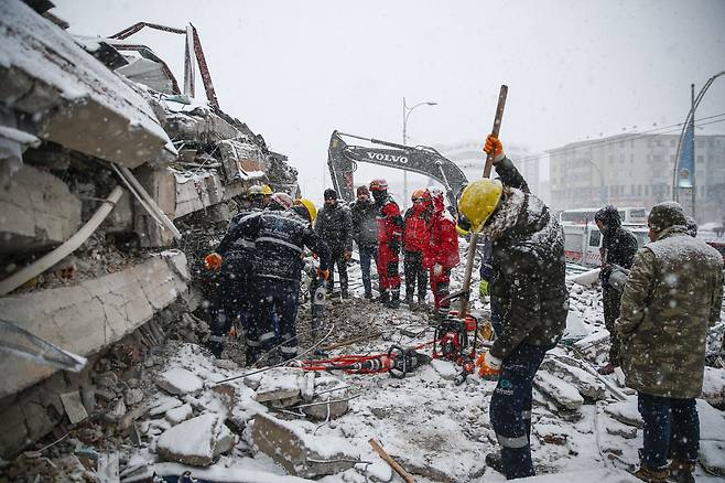 7일(현지 시각) 눈이 내리는 튀르키예 말라티아에서 구조대원들이 지진으로 켜켜이 쌓인 건물 잔해 사이를 수색하고 있다./게티이미지코리아