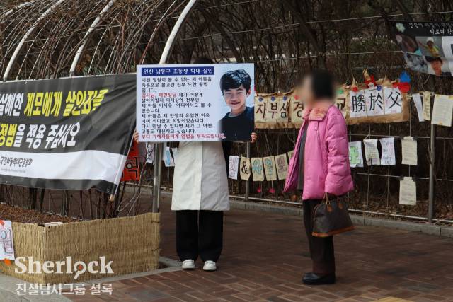 ▲법원 앞을 지나던 한 시민이 정빈 씨가 들고 있는 피켓을 살펴보고 있다. ⓒ셜록