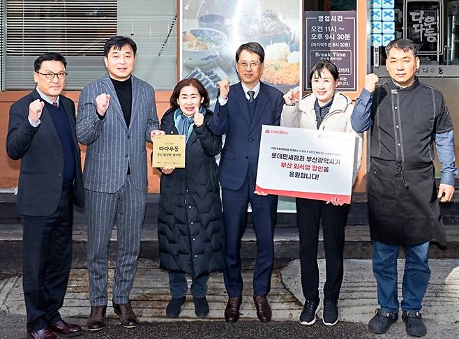 롯데면세점이 2023년 12월 치어럽스 3기에 참여한 부산 지역 소상공인 가게 앞에서 현판식을 진행하는 모습./사진제공=롯데면세점