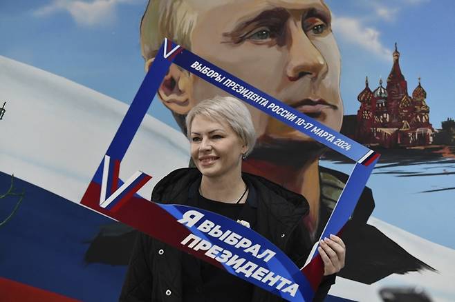블라디미르 푸틴 러시아 대통령의 5선이 확실한 대선이 진행 중인 지난 15일 러시아군이 점령한 우크라이나 도네츠크에서 한 여성이 투표 후 ‘난 대통령(푸틴을 선택했다’는 글귀가 쓰인 액자를 들고 사진을 찍고 있다. AP연합뉴스