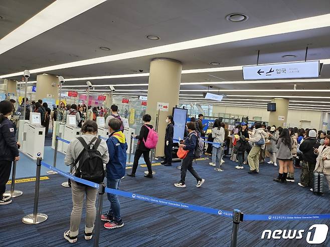 25일 오전 11시쯤 김해국제공항을 통해 입국하고 있는 대만 여행객들이 자동검역심사대(왼쪽 4대)를 통과 하고 있다. 반면 대면 검역심사대(오른쪽)에는 여행객들이 줄을 길게 서 있다.