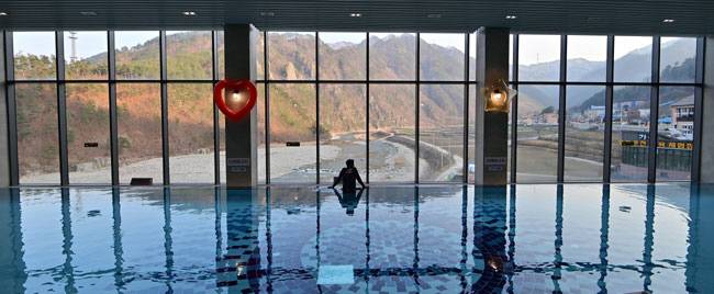 가곡온천의 3층 메인 풀. 전면 창 너머로 병풍바위와 가곡천 물길이 그림처럼 펼쳐진다.