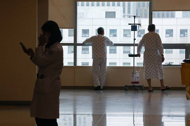 의료대란이 장기화되고 있는 가운데 28일 서울의 한 대학병원에서 의료진 옆으로 환자들이 보인다.    연합뉴스