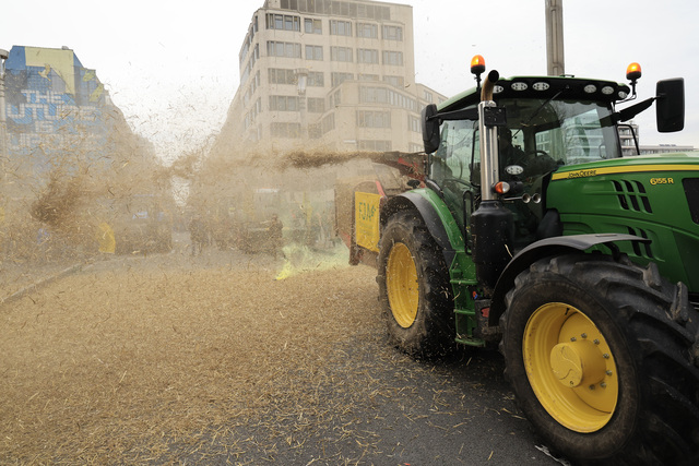 26일 화요일, 브뤼셀의 유럽의회 건물로 이어지는 주요 대로에서 한 농부가 트랙터를 이용해 건초를 뿌리고 있다. AP연합뉴스
