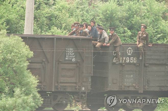 화물열차 타고 가는 북한 주민 고난의 행군 당시 북한 주민들과 북한군들이 화물열차를 타고 중국 연변 삼합지역 두만강 건너편인 함경북도 온성군 신전리 부근을 지나고 있는 모습으로 중국 쪽에서 촬영.
  [연합뉴스 사진]