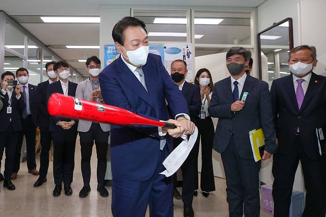 윤석열 대통령이 작년 5월 26일 정부세종청사에서 국정운영실 직원으로부터 국정운영 홈런을 기원하는 메시지가 적힌 야구 방망이를 선물받은 뒤 휘두르고 있다./뉴스1