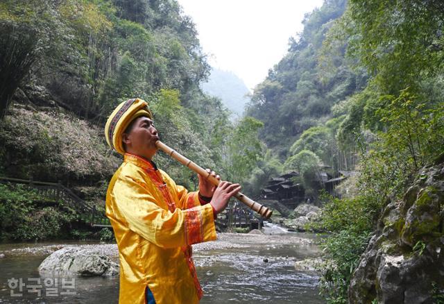 장강삼협 크루즈 삼협인가 투어에서 투자족 남성이 계곡에서 피리를 불고 있다.