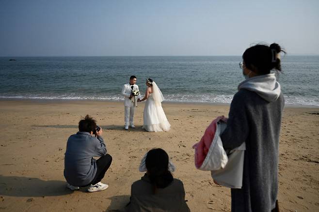 중국 푸젠성의 한 해변에서 예비 신랑 신부가 웨딩 촬영을 하고 있다. (사진=AFP)