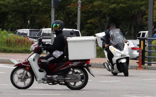 배달 오토바이 운전자(오른쪽)가 안전모도 쓰지 않은 채 운행하고 있다. 뉴스1