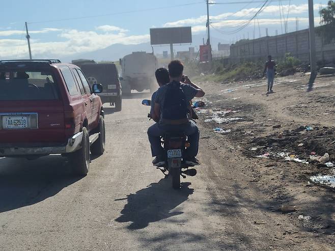 지난달 아이티를 방문했던 최현덕씨가 갱단이 공항으로 가는 길을 막았다는 소식을 듣고 급하게 오토바이를 타고 막히지 않은 길로 이동하고 있는 모습./최현덕