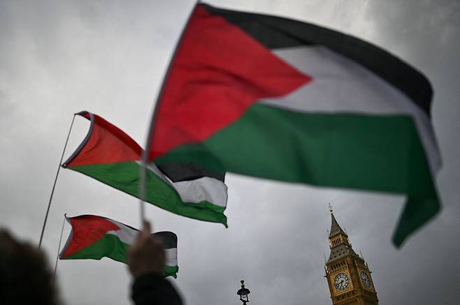 친팔레스타인 운동가들과 지지자들이 17일(현지 시각) 영국 런던 국회의사당 앞에서 영국이 이스라엘에 무기를 수출하는 것을 반대하는 시위를 하며 팔레스타인 국기를 흔들고 있다. / AFP 연합뉴스