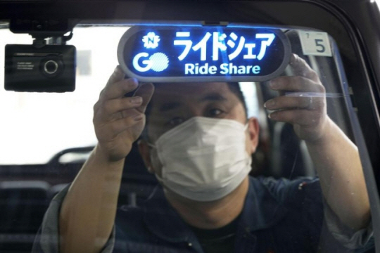 일본 도쿄에서 자가용을 이용한 유료 운송 서비스가 시작된 지난 8일 운전자가 ‘승차 공유’를 뜻하는 ‘라이드 셰어’ 안내판 위치를 조절하고 있다. 연합뉴스