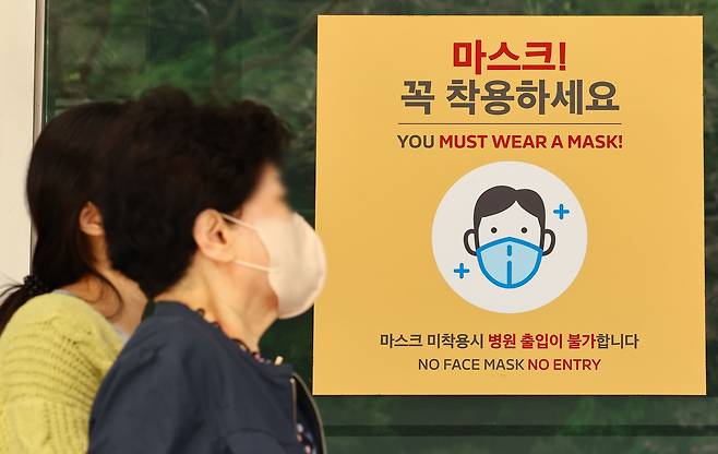 19일 서울 시내 한 대형병원에 게시된 마스크 착용 안내문 앞으로 내원객들이 이동하고 있다./뉴시스