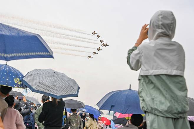 공군 특수비행팀 블랙이글스가 20일 ‘제45회 스페이스 챌린지 2024 in 대구’에서 선보이는 에어쇼를 관람객들이 우산을 받쳐 든 채 지켜보고 있다. 연합뉴스