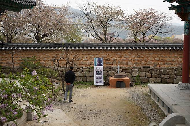 A visitor takes a stroll near a clay fire pit and cast-iron cauldron from "The Glory," which are preserved at Yonghwasa in Cheongju, North Chungcheong Province, April 11. (Lee Si-jin/The Korea Herald)