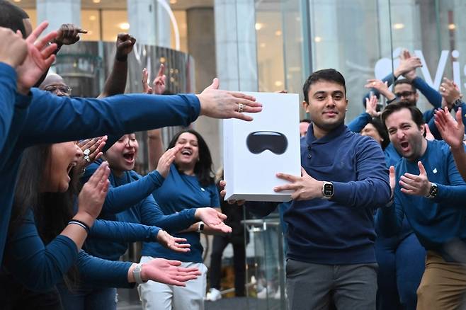 올해 2월 미국 뉴욕에 위치한 애플 매장에서 가장 먼저 비전프로를 구입한 고객이 직원들의 박수를 받으며 걸어나오고 있다. [사진 출처 = AFP 연합뉴스]