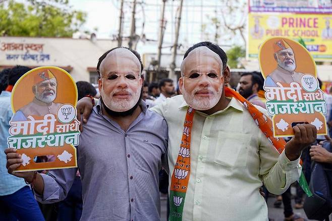 12일(현지시간) 인도 서부 라자스탄주 다우사에서 열린 나렌드라 모디 총리의 총선 유세 현장에서 지지자들이 모디 총리 얼굴 가면을 쓴 채 인도국민당(BJP)의 선거 팸플릿을 들어 보이고 있다.   다우사=AFP연합뉴스