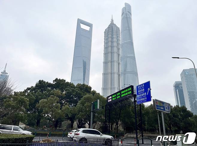 중국 상하이 루자주이 금융지구의 상하이 타워와 다른 고층 빌딩 근처에서 상하이와 선전 주가지수를 보여주는 전광판 밑으로 자동차들이 지나가고 있다. 2024.2.5 ⓒ 로이터=뉴스1 ⓒ News1 정은지 특파원