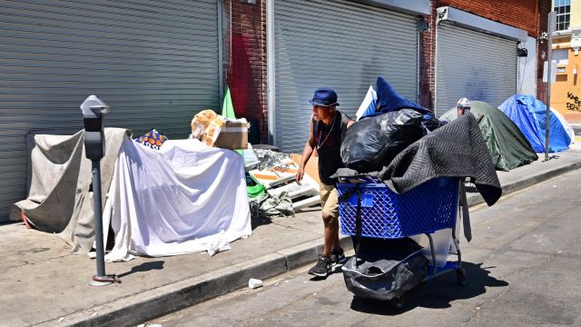 미국 LA에서 노숙자가 텐트 너머로 소지품을 옮기고 있다. AFP연합뉴스