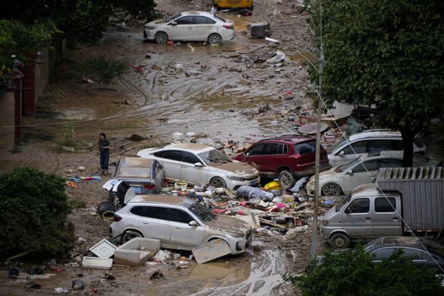 중국 광둥성 둥광시에 폭우가 쏟아진 지난해 9월 한 여성이 진흙과 차량 잔해를 헤쳐 지나가고 있다. 광둥=로이터 연합뉴스